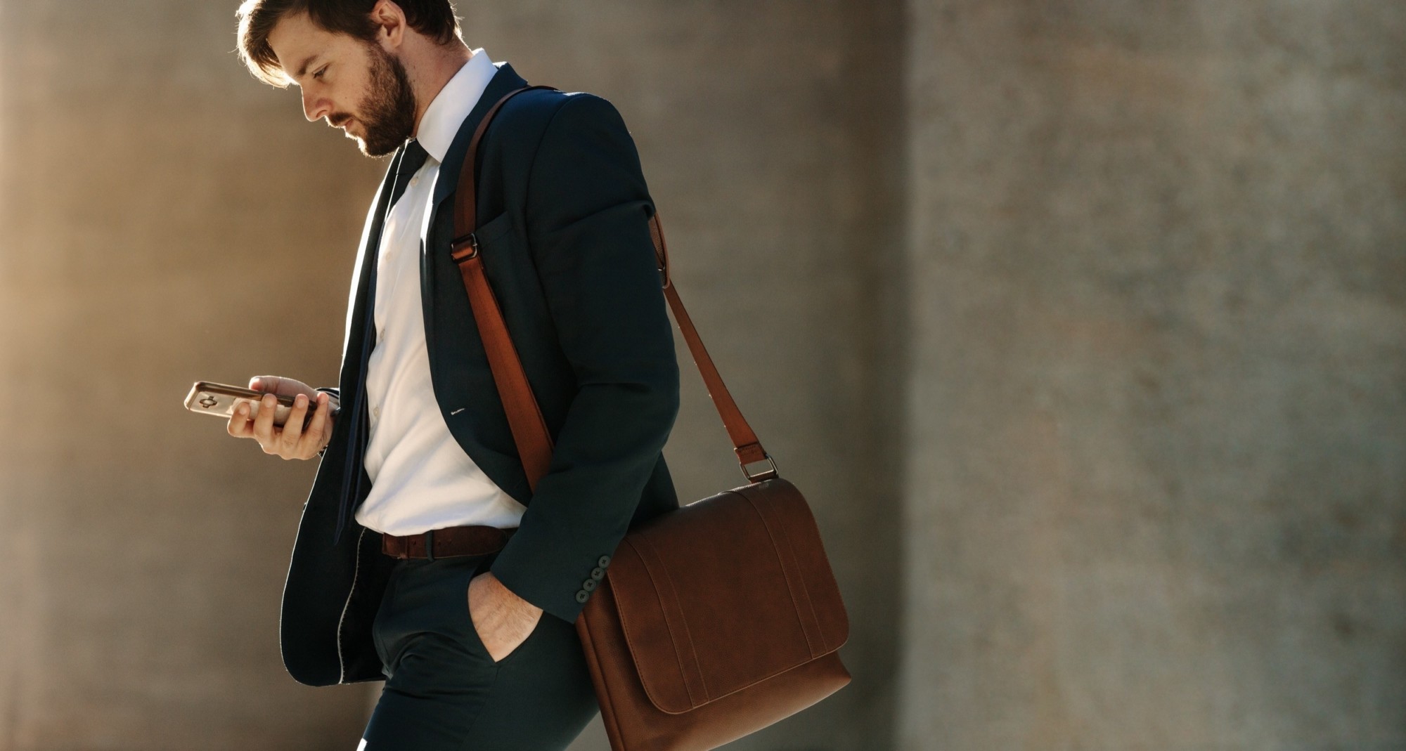 Man using mobile phone while walking on street to office